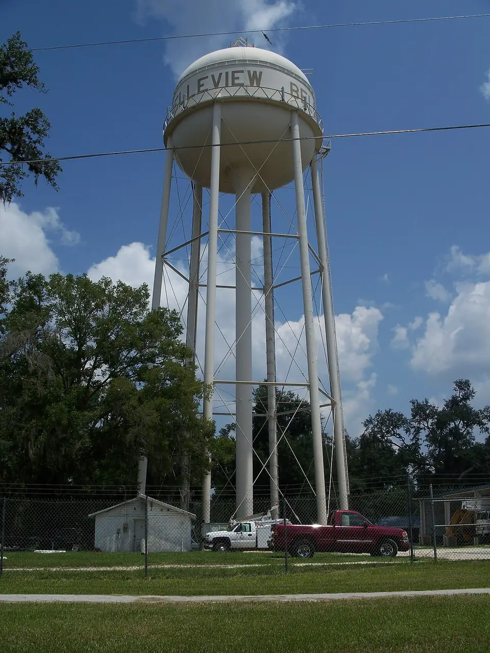 The municipal water tower at Belleview, Marion County, seen above trees against a blue sky.
