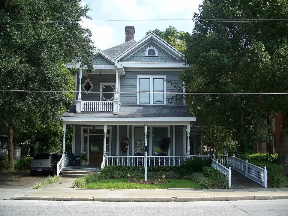A white weatherboard house with a deep front porch and mature planting in Ocala’s historic district.