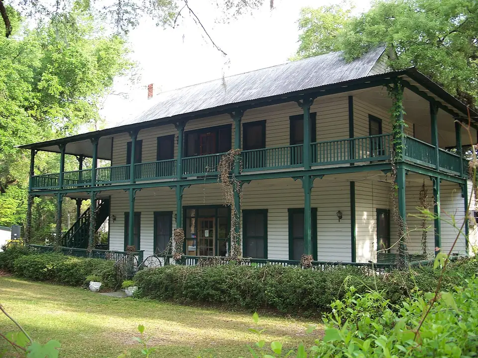 A two-storey wood frame house with wraparound porches and a metal roof, shaded by oaks in Orange Springs, Marion County.