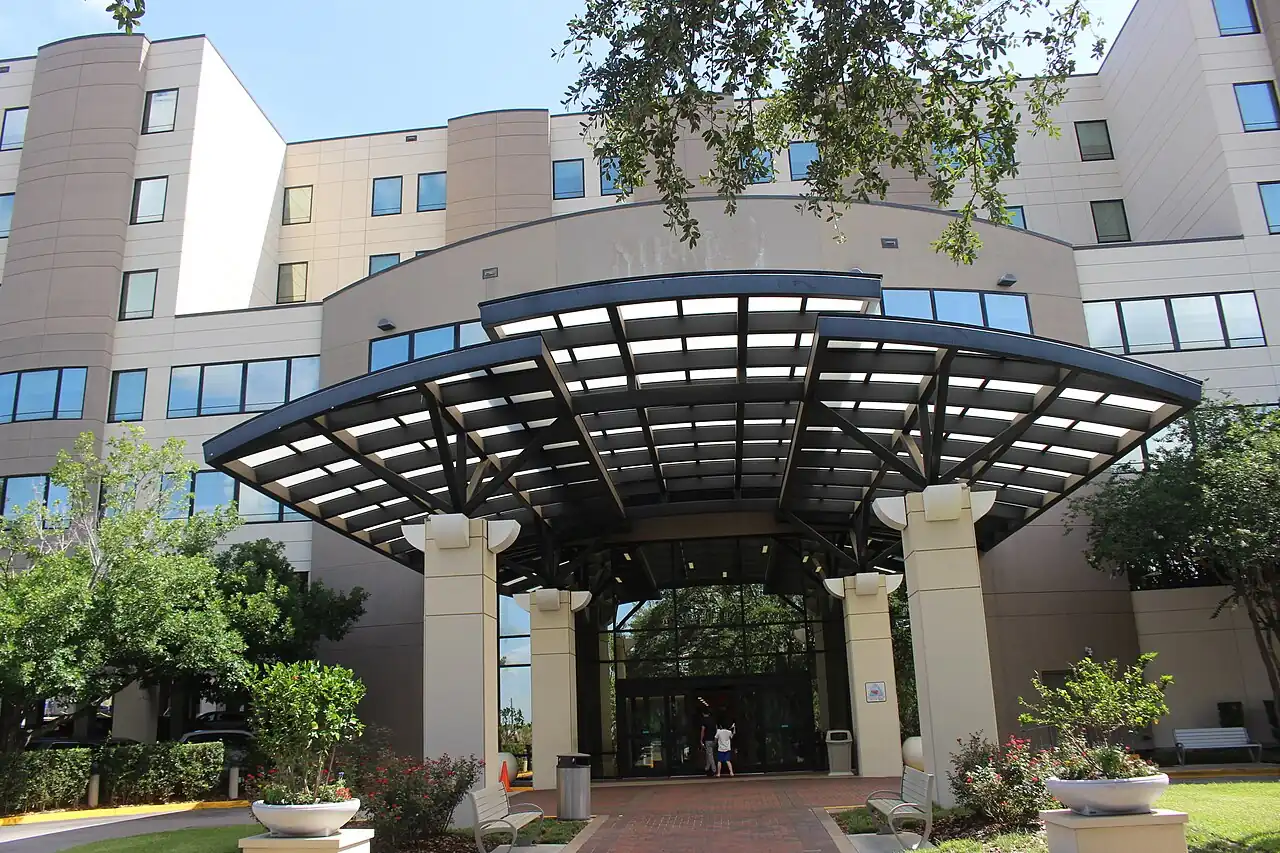 The AdventHealth Ocala hospital building, a multi-storey brick and glass facade behind palms.