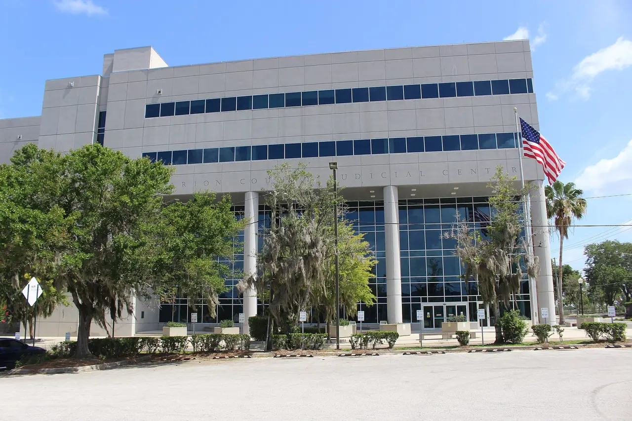 The Marion County Judicial Center in Ocala, a low modern government building behind a lawn and palms.