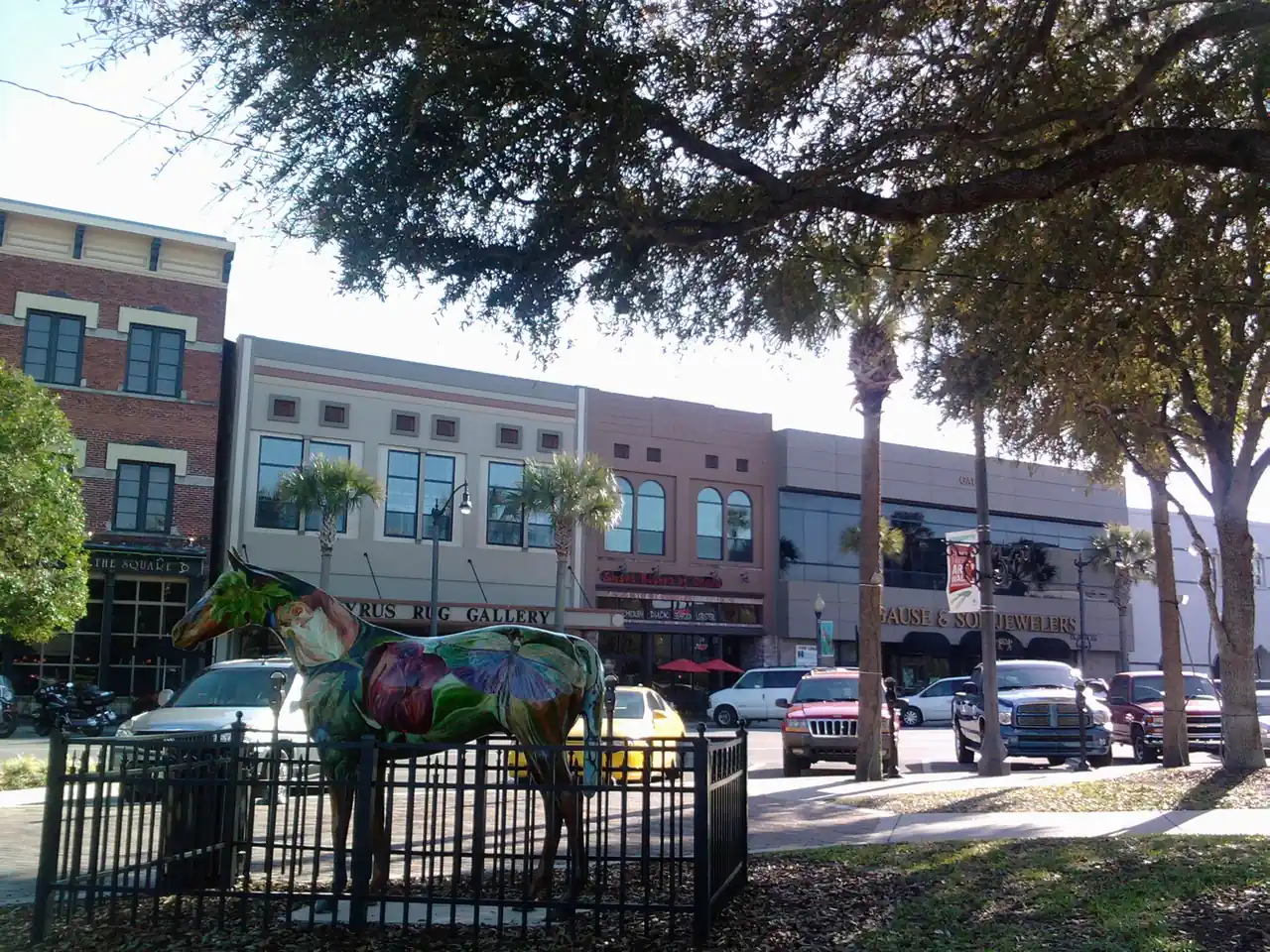 A view along a street off Ocala's downtown square, low brick storefronts under mature shade trees.
